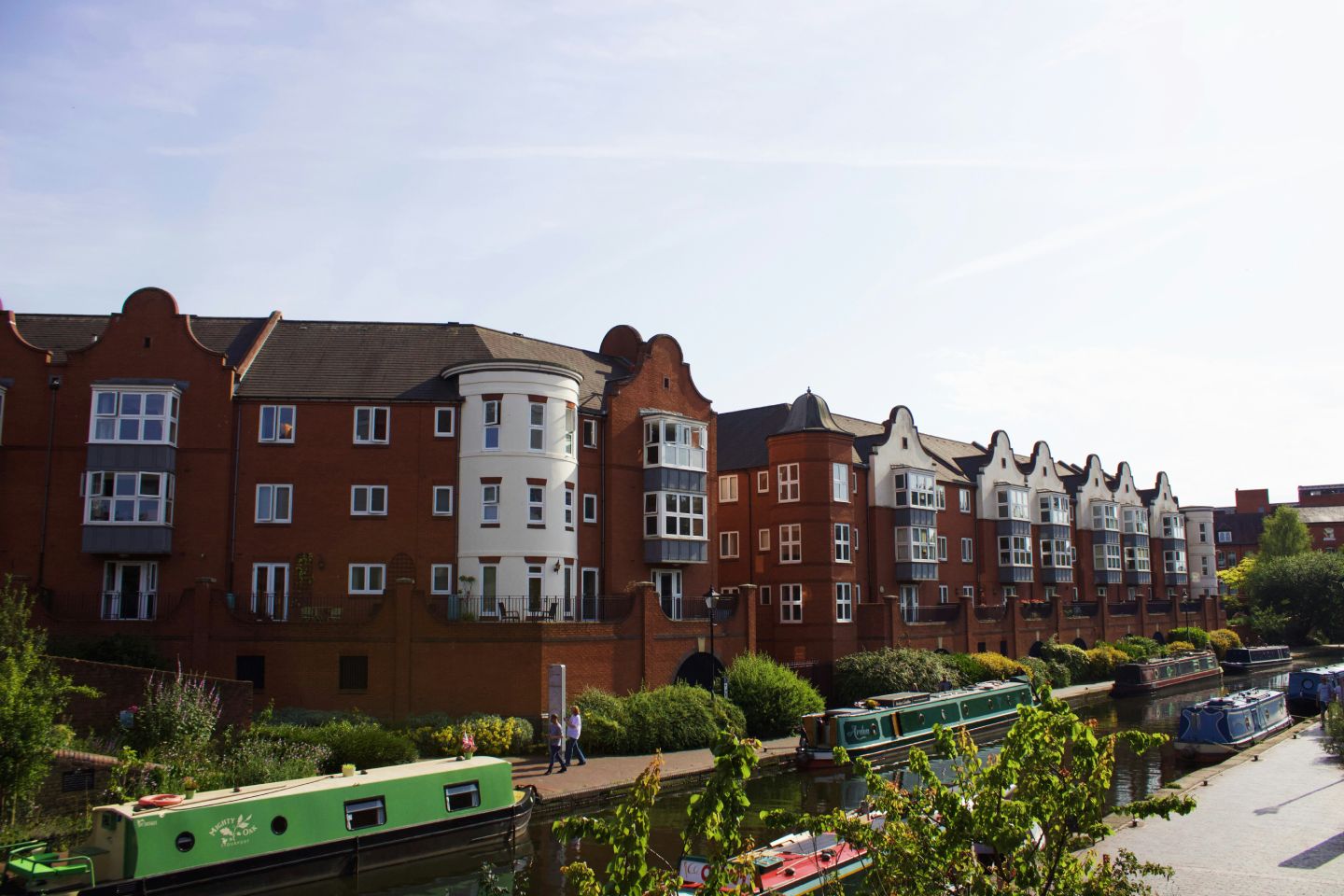 Apartment buildings line a canal with narrowboats.